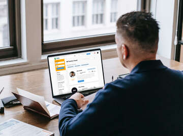 A photo of a student sitting at his computer and looking at a list of teachers available on Teacher Creature